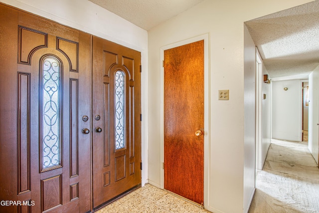 foyer entrance featuring a textured ceiling and baseboards