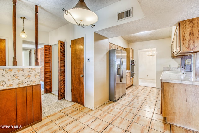 kitchen with stainless steel fridge with ice dispenser, visible vents, an inviting chandelier, a sink, and a textured ceiling