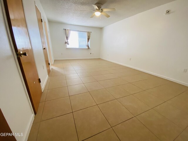 spare room with baseboards, a textured ceiling, a ceiling fan, and light tile patterned flooring