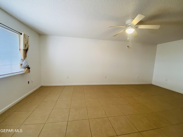 unfurnished room featuring ceiling fan, light tile patterned flooring, baseboards, and a textured ceiling