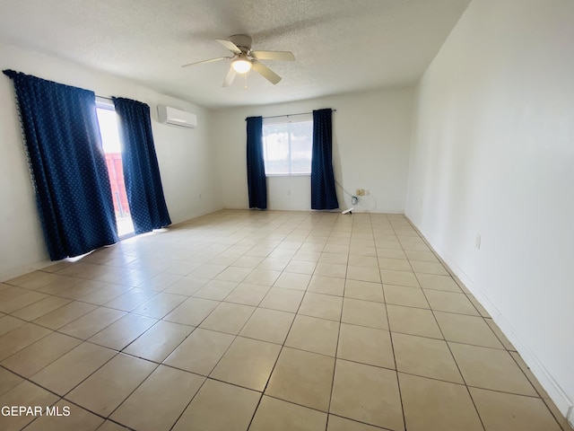 empty room featuring light tile patterned floors, a textured ceiling, a ceiling fan, and a wall unit AC