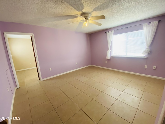 empty room featuring light tile patterned floors, baseboards, a textured ceiling, and ceiling fan