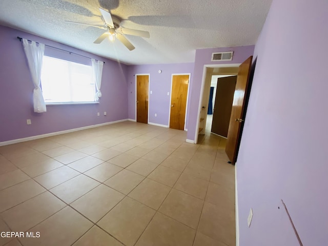 unfurnished bedroom with visible vents, baseboards, light tile patterned floors, and a textured ceiling