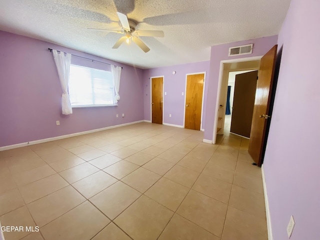 unfurnished bedroom featuring light tile patterned floors, ceiling fan, a textured ceiling, visible vents, and baseboards