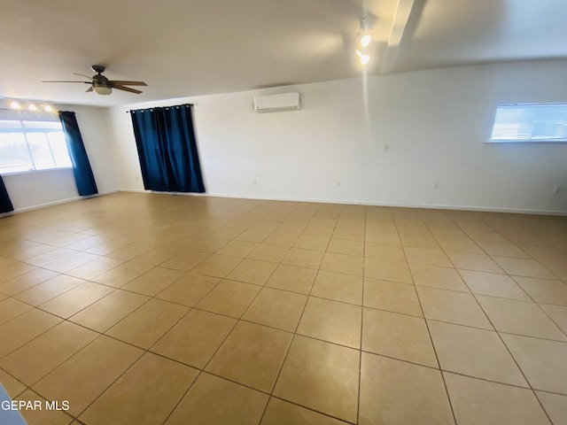 unfurnished room featuring a wall mounted AC, baseboards, light tile patterned flooring, and ceiling fan