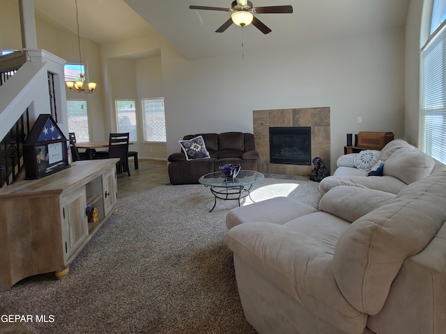 living area featuring light colored carpet, baseboards, ceiling fan with notable chandelier, and a tile fireplace