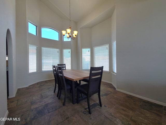 dining space with stone finish flooring, baseboards, a chandelier, and high vaulted ceiling