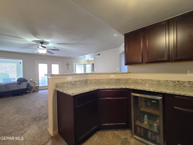 kitchen with dark brown cabinets, beverage cooler, a ceiling fan, a peninsula, and visible vents
