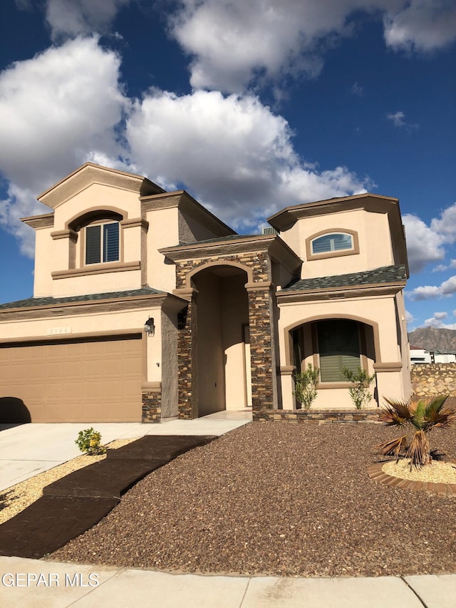 mediterranean / spanish house with stucco siding, driveway, a garage, and stone siding