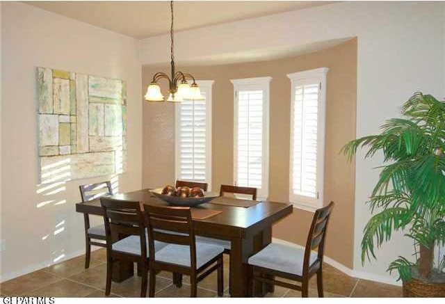 dining space featuring plenty of natural light, a chandelier, tile patterned flooring, and baseboards