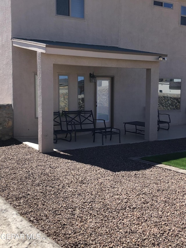 back of house with stucco siding and a porch