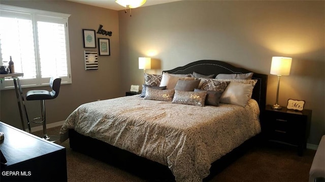 bedroom featuring dark carpet and baseboards