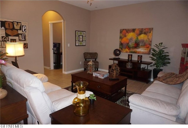 tiled living area with arched walkways and baseboards