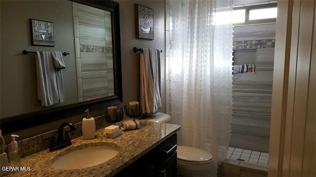 full bathroom featuring tiled shower, vanity, and toilet