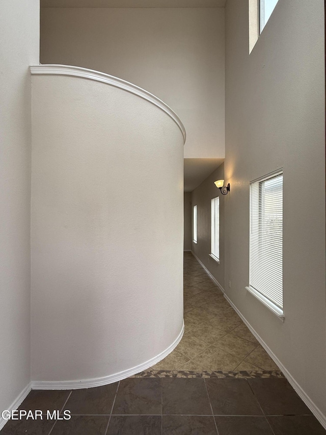 14368 N Cave Dr, El Paso, TX 79938 - hallway featuring dark tile patterned floors, a towering ceiling, and baseboards