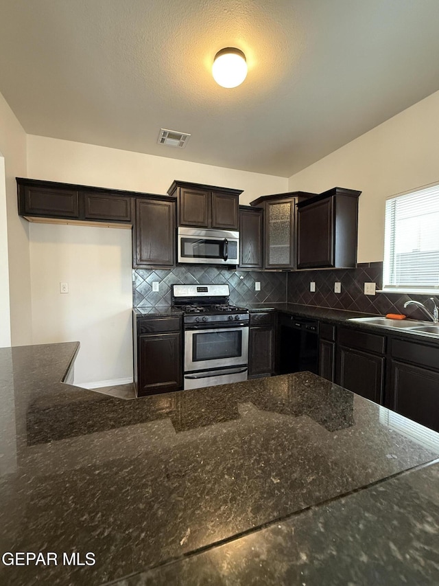 14368 N Cave Dr, El Paso, TX 79938 - kitchen featuring dark stone counters, decorative backsplash, dark brown cabinets, and stainless steel appliances