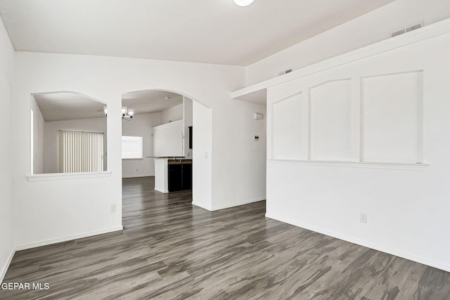 12729 Raul Mendiola Ln, El Paso, TX 79938 - unfurnished living room featuring dark wood finished floors, arched walkways, baseboards, and a chandelier