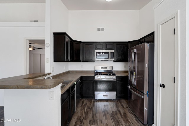 12729 Raul Mendiola Ln, El Paso, TX 79938 - kitchen with stainless steel appliances, a sink, a ceiling fan, dark wood-type flooring, and a peninsula