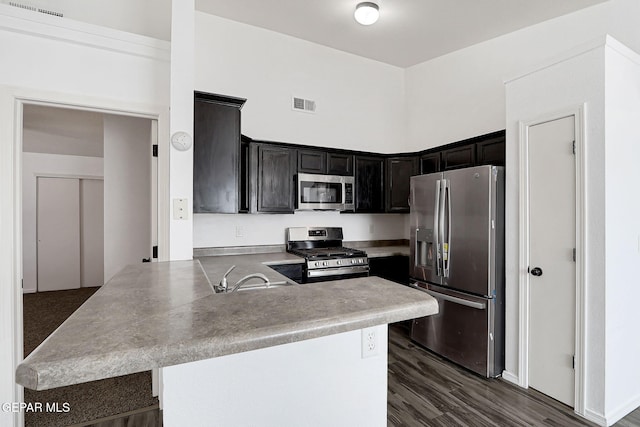 12729 Raul Mendiola Ln, El Paso, TX 79938 - kitchen with appliances with stainless steel finishes, a peninsula, a sink, light countertops, and dark wood-type flooring