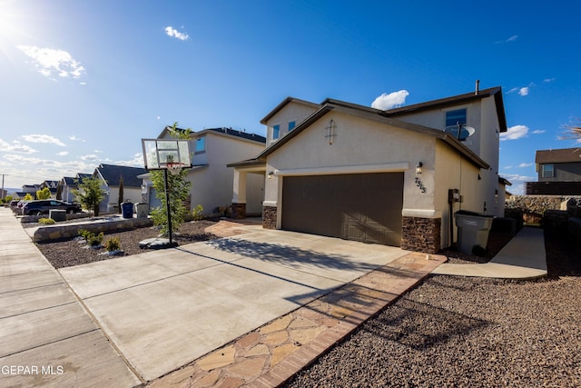 view of front of home featuring an attached garage, concrete driveway, stone siding, and stucco siding