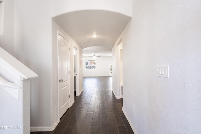 hallway featuring dark wood finished floors and baseboards