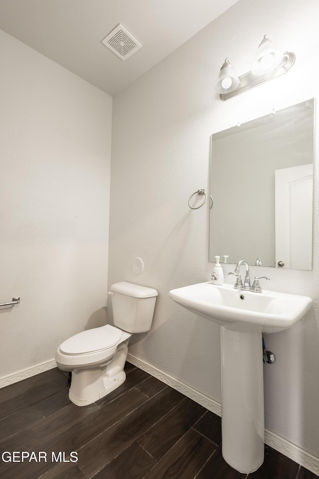 bathroom featuring toilet, baseboards, and wood finished floors