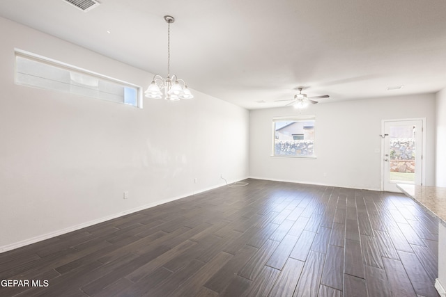 unfurnished room featuring a ceiling fan, dark wood-type flooring, a chandelier, and baseboards