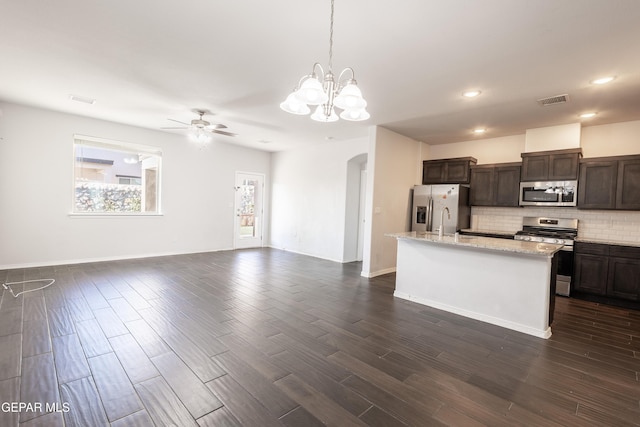 kitchen featuring appliances with stainless steel finishes, arched walkways, ceiling fan, dark brown cabinetry, and decorative backsplash