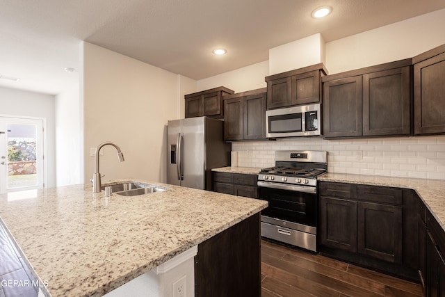 kitchen featuring stainless steel appliances, a sink, dark brown cabinetry, tasteful backsplash, and recessed lighting