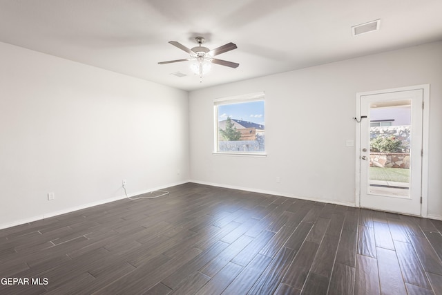 empty room featuring a ceiling fan, dark wood-style flooring, and baseboards