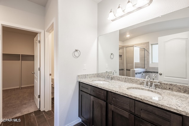 full bathroom with a shower stall, double vanity, a walk in closet, toilet, and wood finished floors