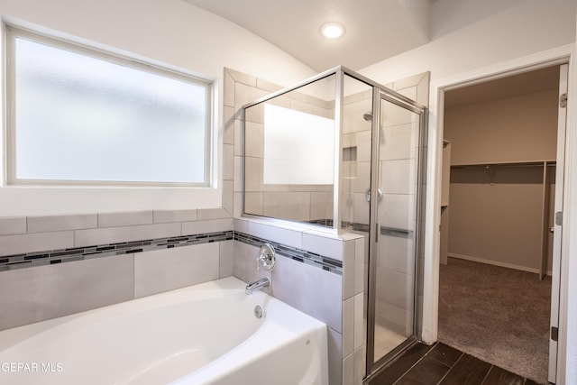 bathroom with a stall shower, a garden tub, a spacious closet, and recessed lighting
