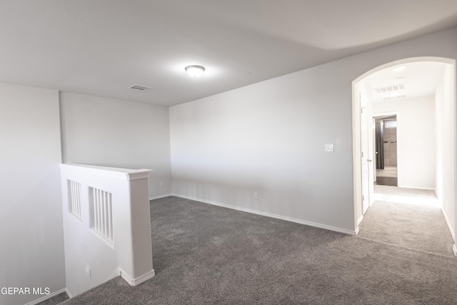 unfurnished room featuring carpet floors, arched walkways, and baseboards