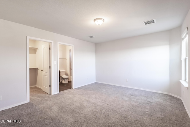 unfurnished bedroom with carpet flooring, a spacious closet, and baseboards