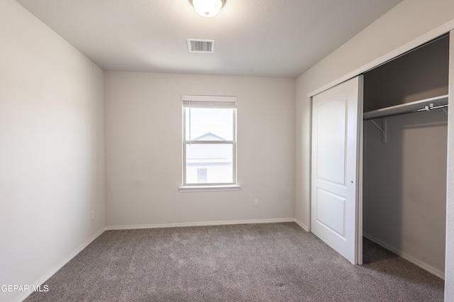 unfurnished bedroom with carpet, a closet, and baseboards