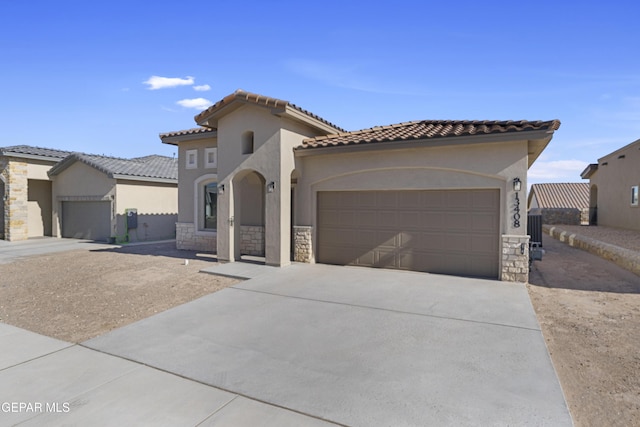 mediterranean / spanish home with stone siding, an attached garage, stucco siding, and concrete driveway