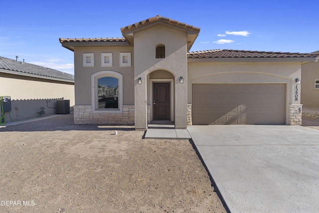 mediterranean / spanish home featuring a tile roof, central air condition unit, driveway, an attached garage, and stucco siding