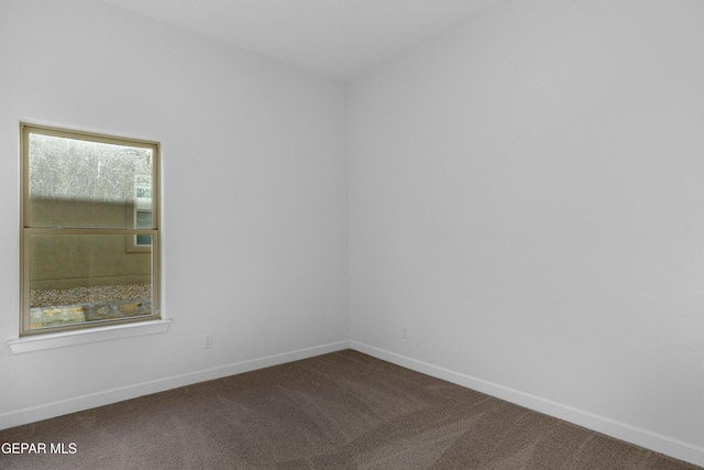 spare room with dark carpet and baseboards