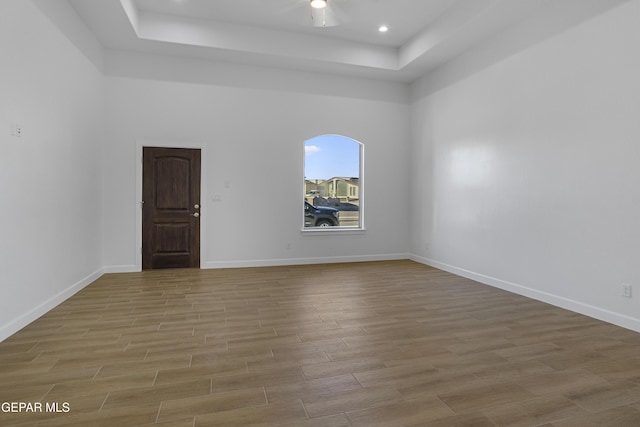 unfurnished room featuring baseboards, wood finished floors, and a raised ceiling