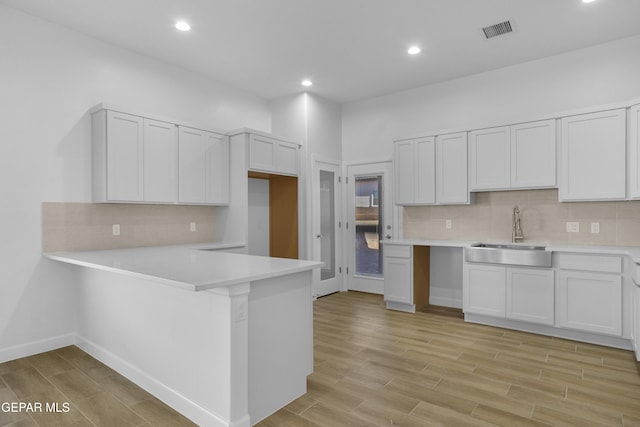 kitchen with backsplash, light countertops, visible vents, a sink, and light wood-style floors