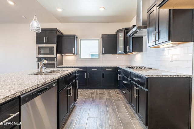 kitchen with wall chimney range hood, tasteful backsplash, a sink, wood tiled floor, and stainless steel appliances