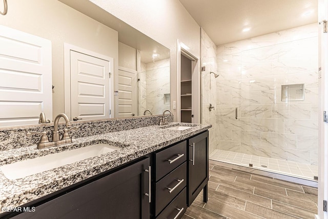 full bath featuring double vanity, wood finish floors, a stall shower, and a sink