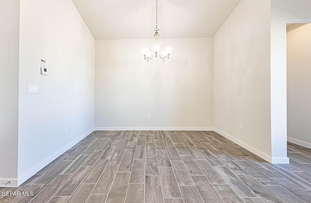 empty room featuring wood finished floors, a chandelier, and baseboards