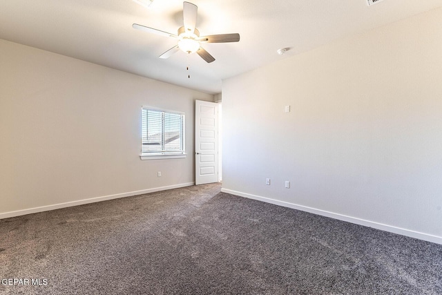 spare room with a ceiling fan, dark colored carpet, and baseboards