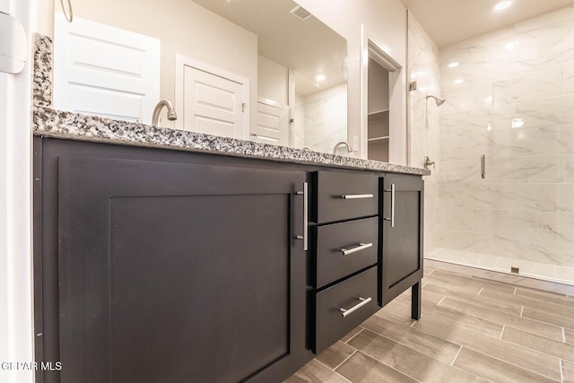 bathroom with recessed lighting, a stall shower, wood tiled floor, and double vanity