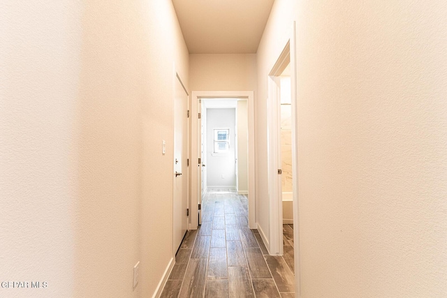 hall featuring dark wood-style flooring and baseboards