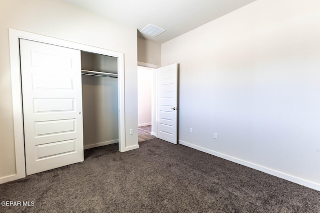 unfurnished bedroom with dark colored carpet, visible vents, baseboards, and a closet