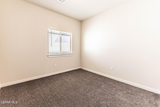 unfurnished room with dark carpet, visible vents, and baseboards