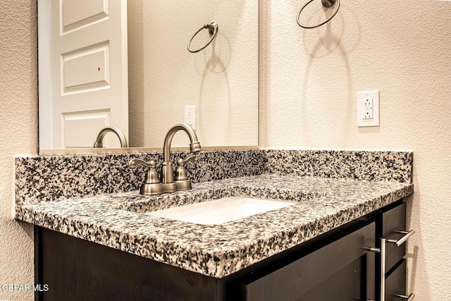 bathroom featuring a textured wall and vanity
