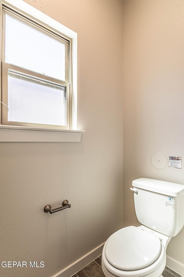 bathroom featuring baseboards, wood finished floors, and toilet